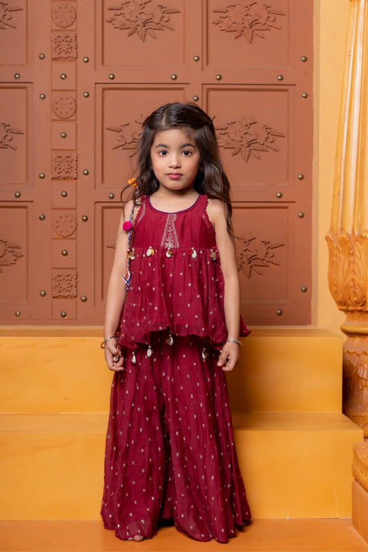 Maroon kids festive set with embroidered peplum top and flared skirt, highlighted with cowrie shell detailing. - Kirti Agarwal