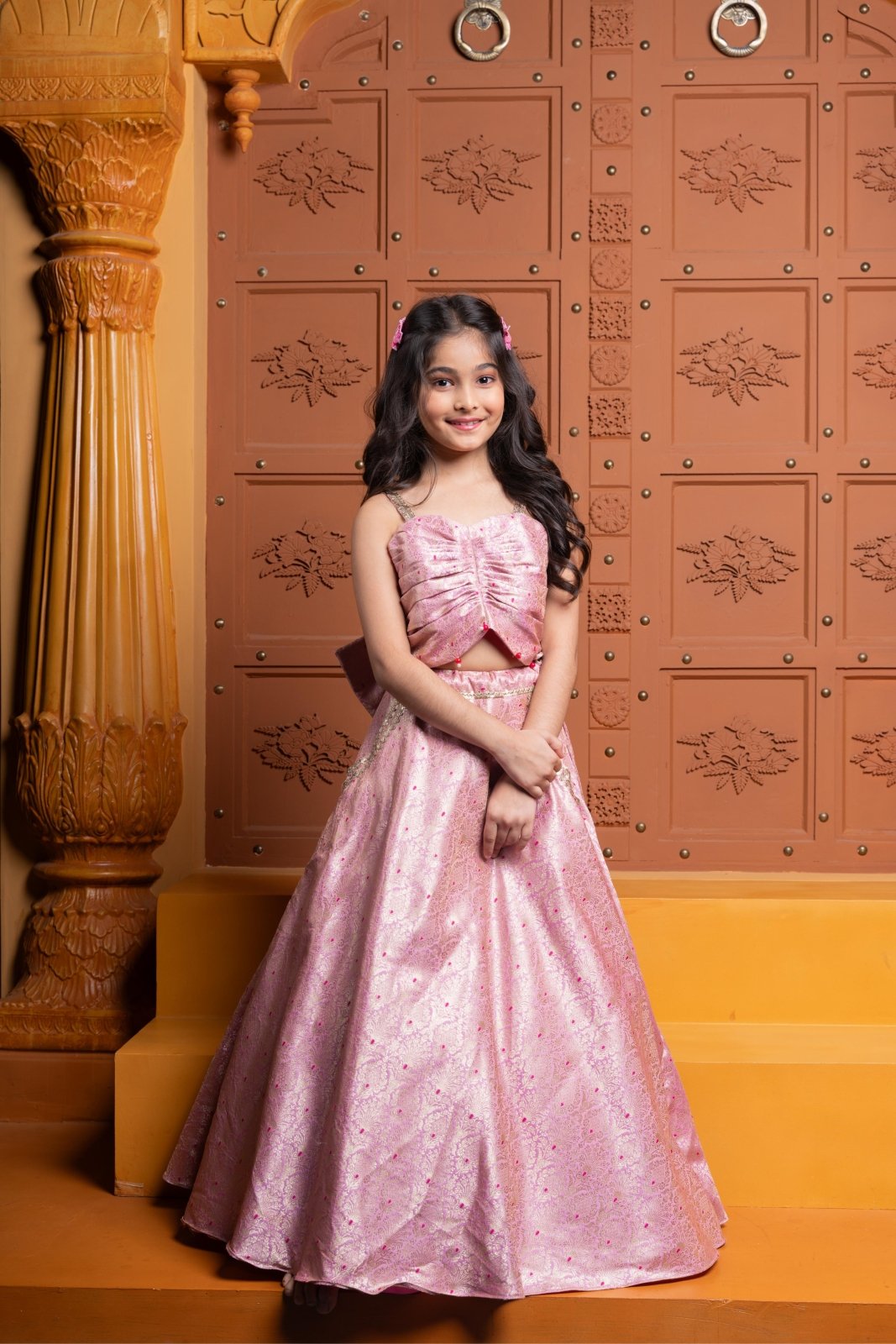 Elegant pink brocade lehenga set for girls with stylish ruched crop top, embroidered pockets, and statement back bow – perfect kids ethnic wear for weddings and parties - Kirti Agarwal