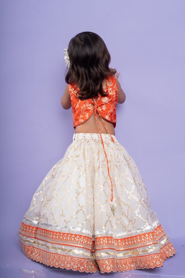 Festive orange brocade top with a golden - patterned white lehenga, perfect for celebrations - Kirti Agarwal